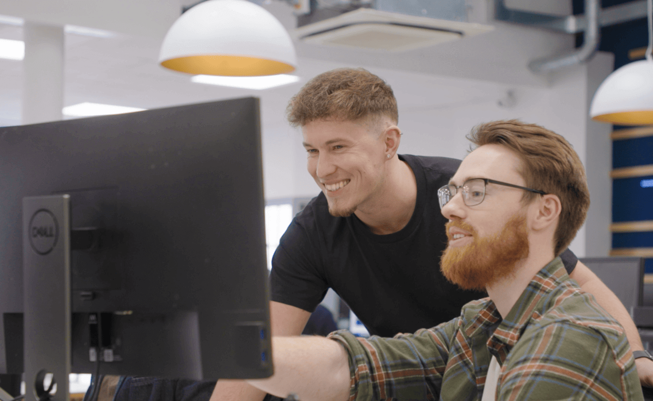 two men smiling at monitor screen