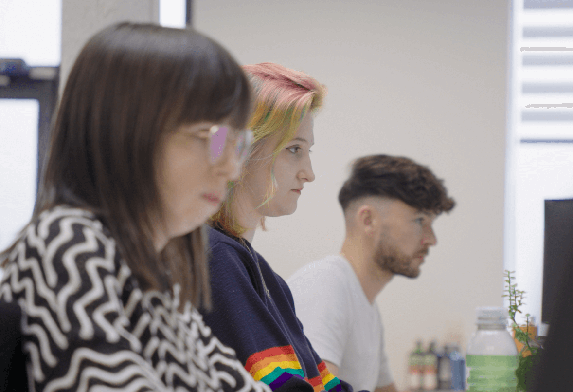 three workers sitting atscreens